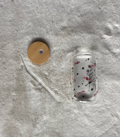 Glass can cup with glass straw and bamboo lid. Design on the glass cup is the Aries zodiac symbol, star constellation, flower and the text Aries on the backside